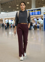 A woman in 98degreenorth Dark Wine Women’s Fleece Flared Sweatpants walks through an airport with a phone and backpack.