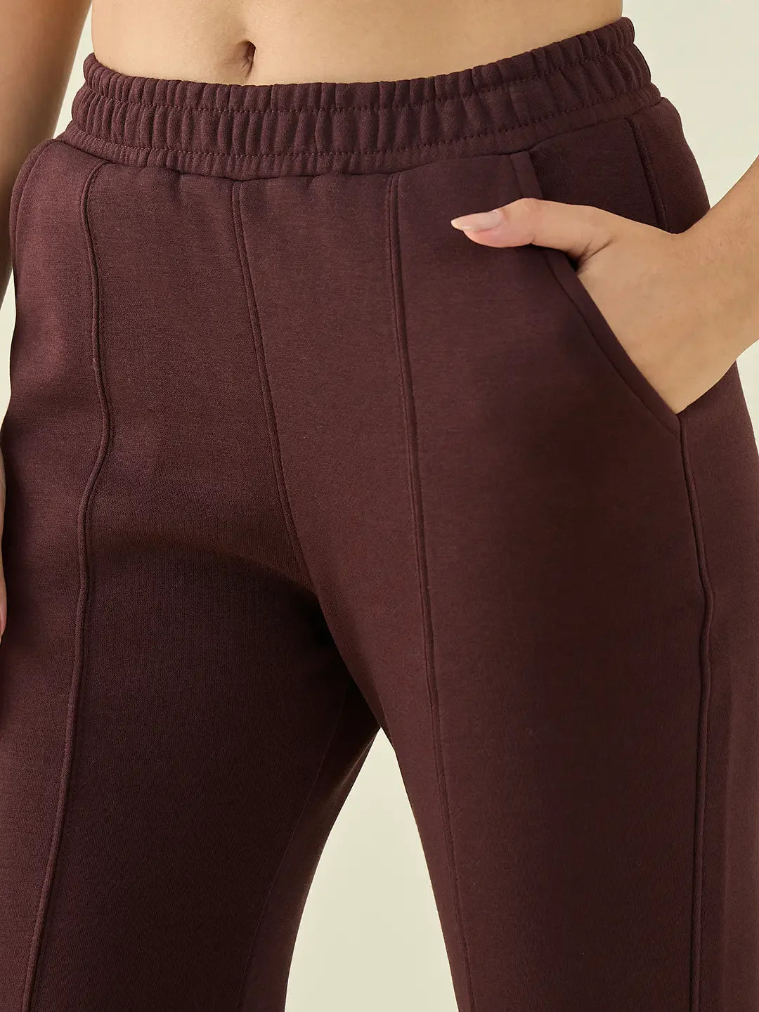 A woman wears 98degreenorth Dark Wine Fleece Flared Sweatpants—warm bootcut winter pants, one hand in pocket.