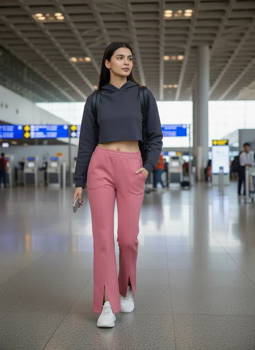 Woman in 98degreenorth dusty pink fleece bootcut sweatpants walks through an airport, phone and backpack in hand.