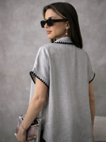 Woman in a Grey Whipstitch Trim Cotton Shirt by 98degreenorth, wearing sunglasses, clutch in hand, side view.