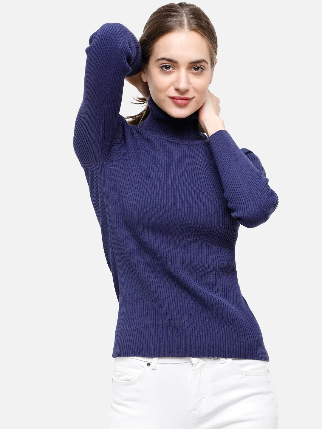 Model in 98degreenorth Ink Blue Ribbed Women’s Turtleneck Sweater poses with white pants against a plain background.