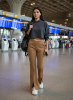 A woman in a cropped hoodie and 98degreenorth Light Coffee Melange Flared Fleece Sweatpants walks through an airport.
