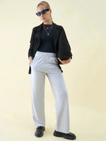 Woman in sunglasses and layered necklaces wears 98degreenorth Luxe Lounge Light Grey Wide Leg Pintuck Trackpants.