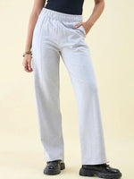 Person in 98degreenorth Light Grey Wide Leg Pintuck Trackpants, black top, and chunky shoes against a beige backdrop.