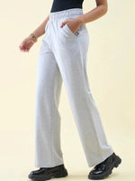 Person wearing 98degreenorth Light Grey Wide Leg Pintuck Trackpants, black top, black shoes, bracelets, hands in pockets.