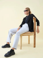 Woman in sunglasses, black blazer, and 98degreenorth Luxe Lounge Light Grey Wide Leg Pintuck Trackpants on chair.