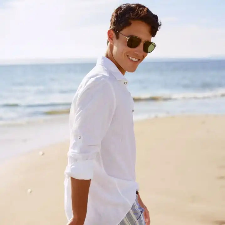 Man wearing sunglasses and a white shirt on a beach