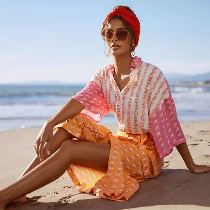 Woman in colorful outfit sitting on a beach with ocean view