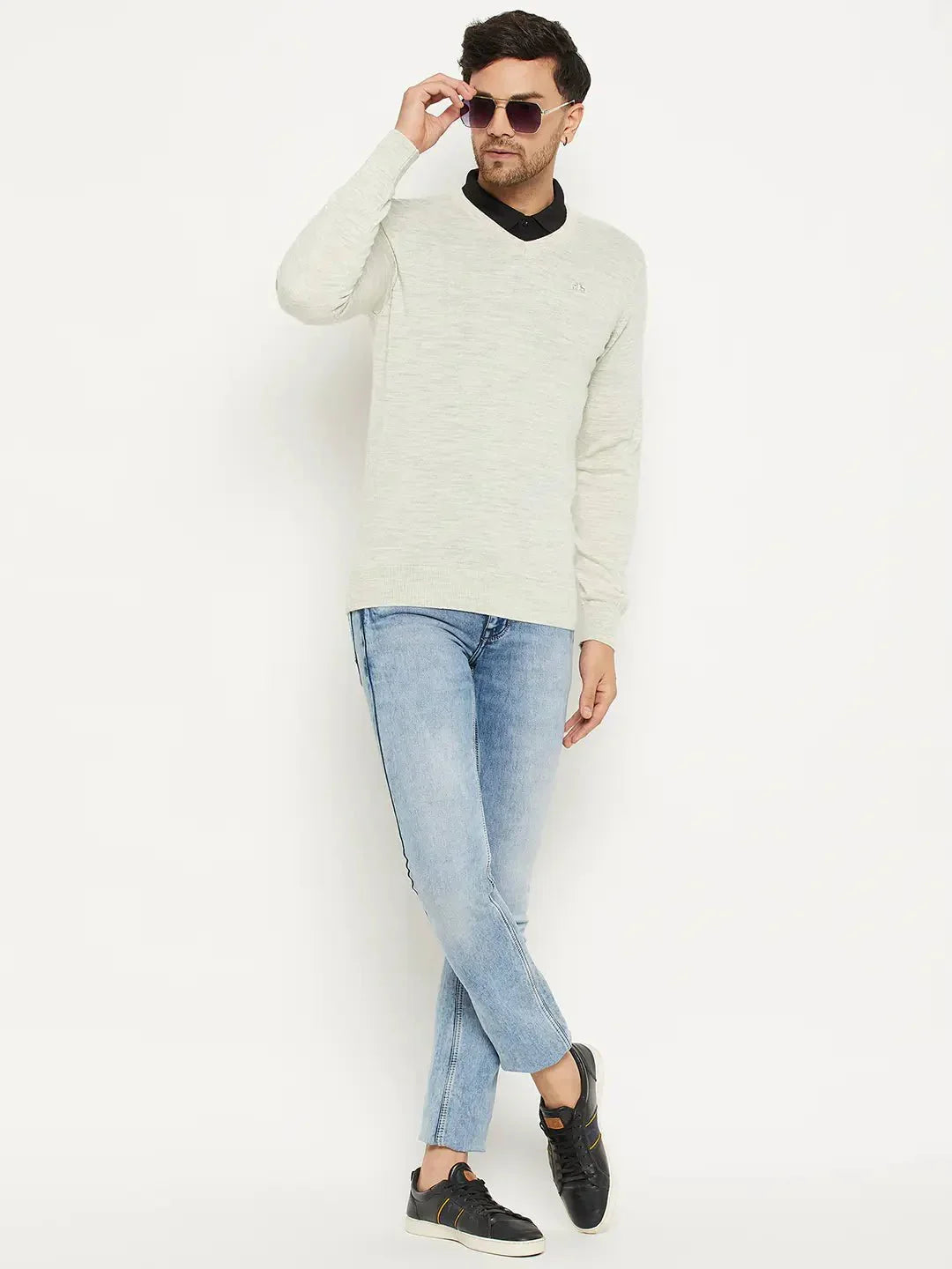 Man in sunglasses wearing a 98degreenorth Men Merino Wool Ecru V-Neck Pullover, blue jeans, and black sneakers.