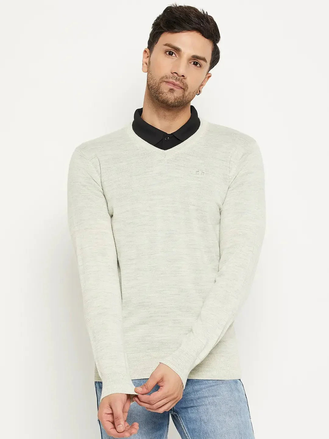 Man in 98degreenorth Men Merino Wool Ecru V-Neck Pullover over black shirt and blue jeans, against white background.