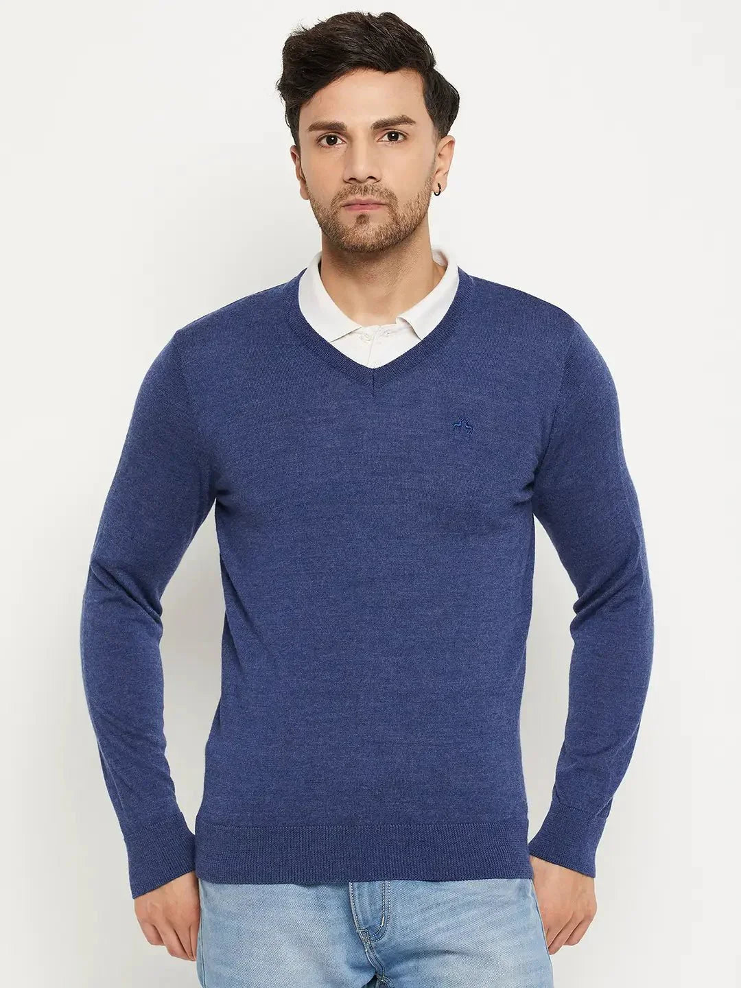 Man wears 98degreenorth Men Merino Wool V-Neck Pullover - Light Denim over a white shirt with light blue jeans.
