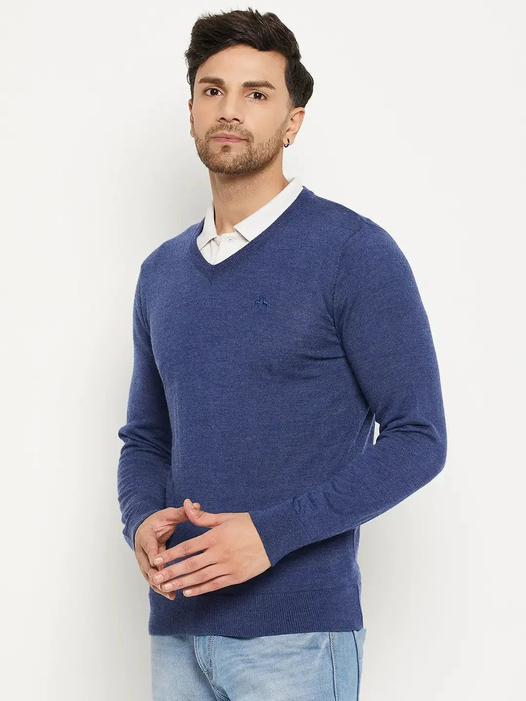 Man wears 98degreenorth Men Merino Wool V-Neck Pullover in Light Denim over a white shirt, against a white background.