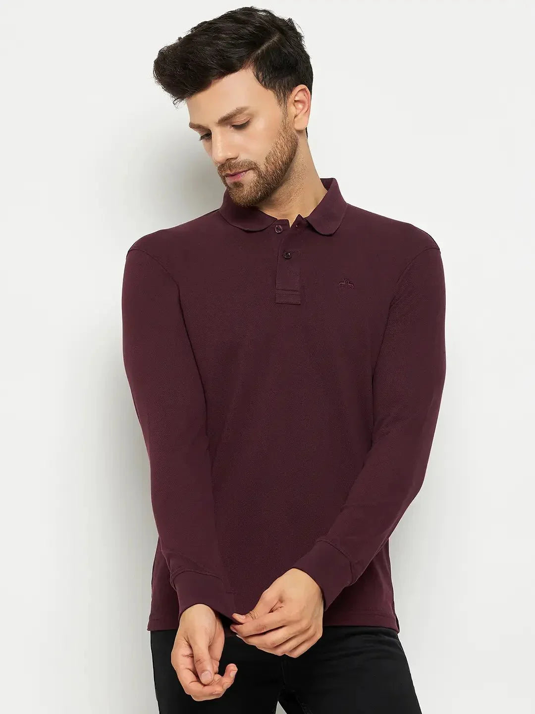 Man in a 98degreenorth Men Polo Collar Full Sleeves Dark Wine T-shirt and black pants, touching his sleeve.