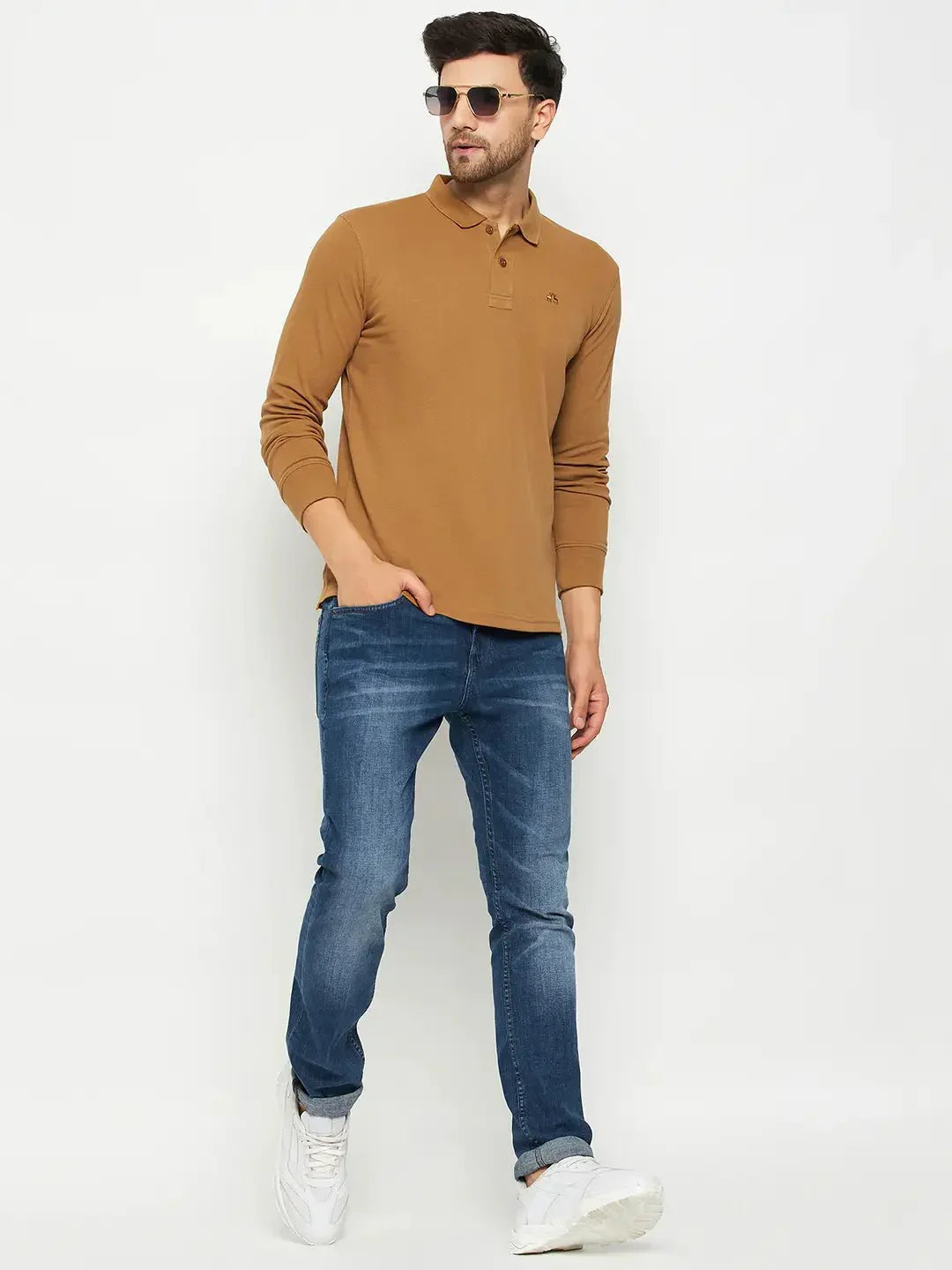 Man in a 98degreenorth Men Polo Collar Full Sleeves Khakhi T-shirt, blue jeans, and sunglasses poses against a plain background.