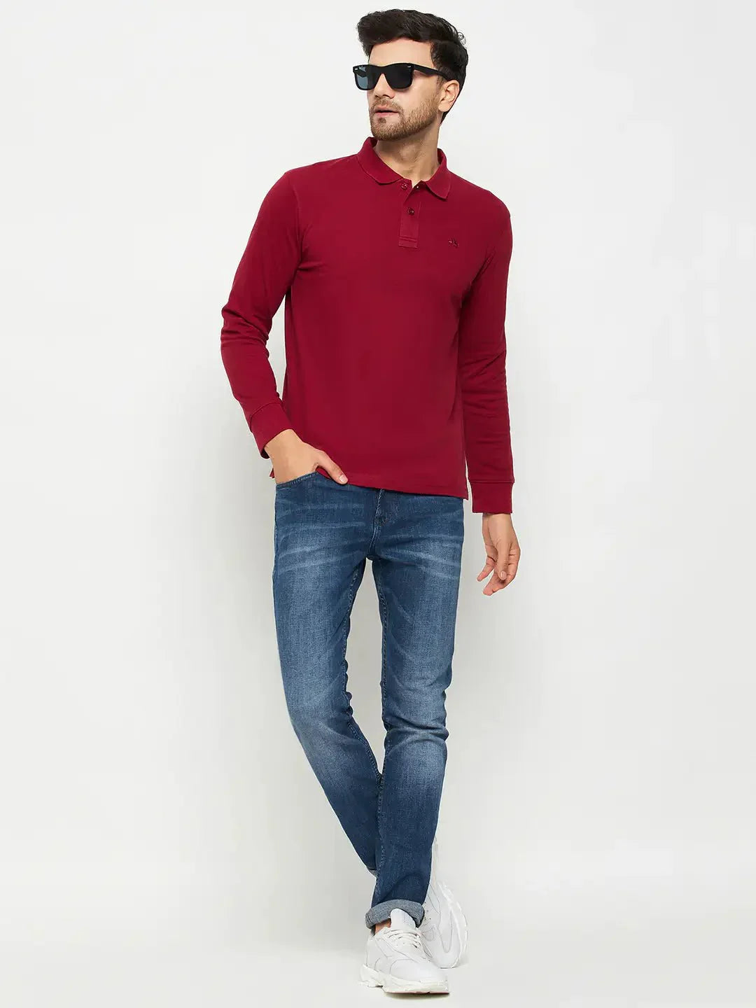 Man wearing a 98degreenorth Men Polo Collar Full Sleeves Maroon T-shirt, blue jeans, and white sneakers.