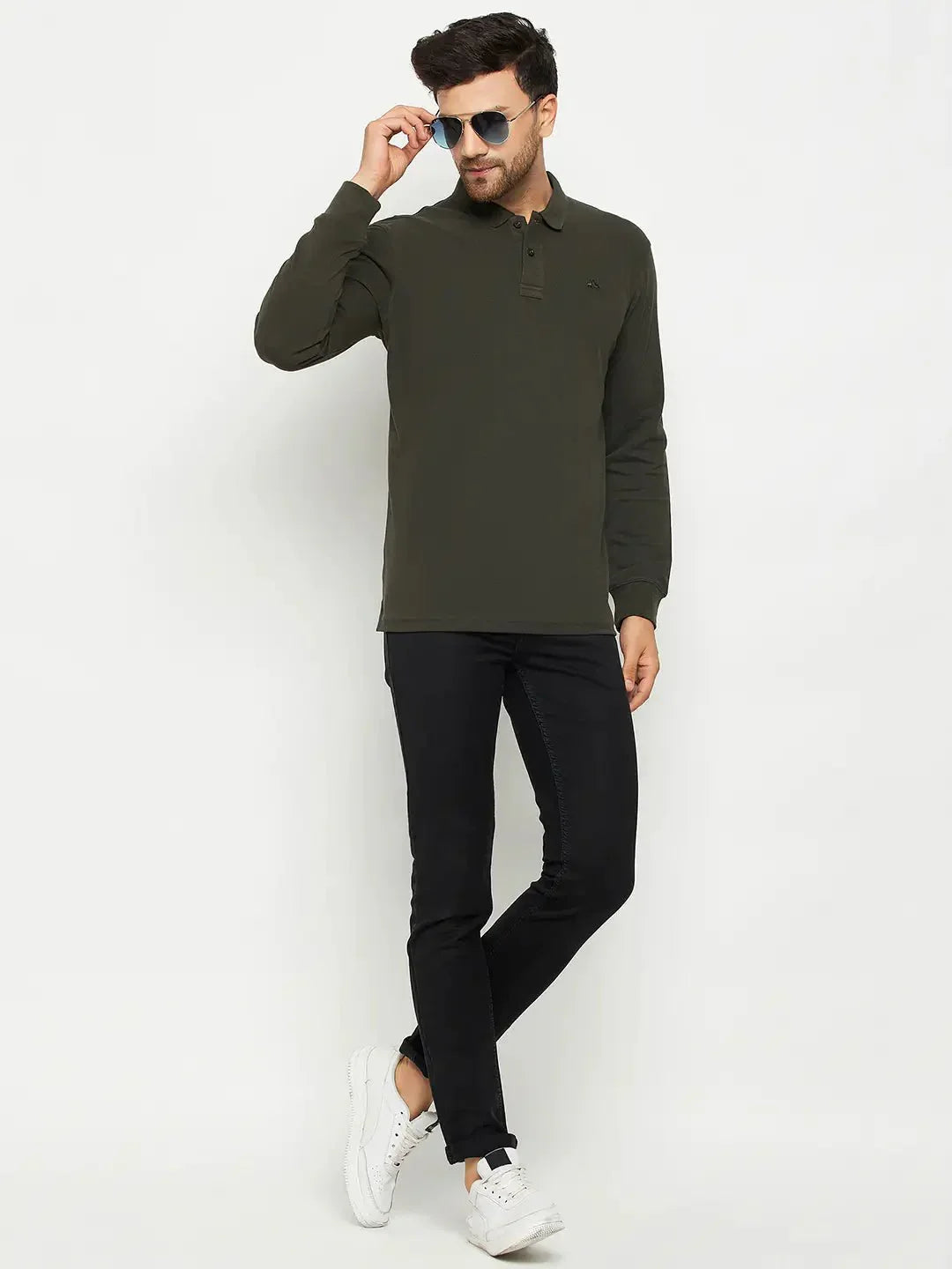 Man wears a 98degreenorth olive Men Polo Collar Full Sleeves T-shirt, black pants, and white sneakers against a white background.