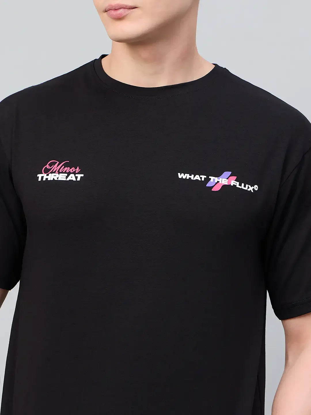 A person wears a 98degreenorth Men Typography Black Printed Round Neck T-shirt with Minor THREAT and WHAT THE FLUX logos.