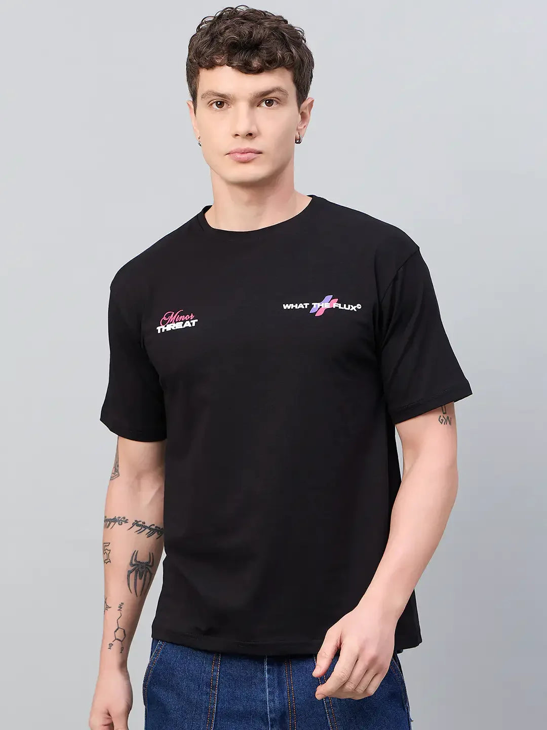 Man with short curly hair wears a 98degreenorth Men Typography Black Printed Round Neck T-shirt and blue jeans.