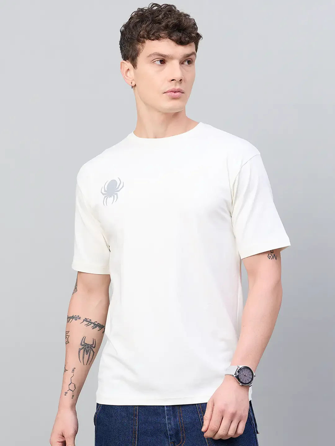 Young man in a 98degreenorth Offwhite Printed T-shirt, blue jeans, and tattoos—ideal for streetwear style.