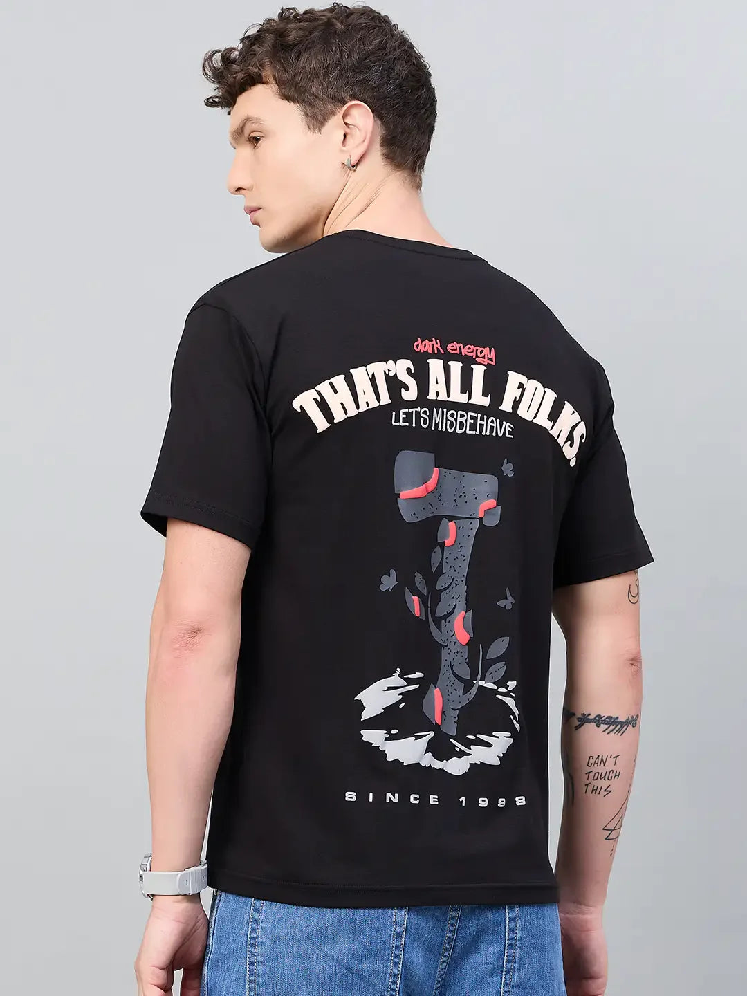 Young man in a 98degreenorth Men Typography Printed Black Round Neck T-shirt—ideal for streetwear enthusiasts.