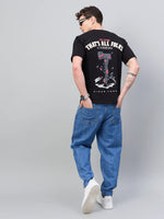 Man in 98degreenorth black typography print tee, blue jeans, white sneakers, sunglasses; facing away.