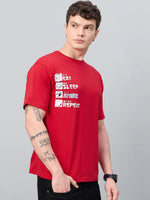A young man in an oversized 98degreenorth Men Typography Printed Round Neck Red T-shirt stands against a grey background.