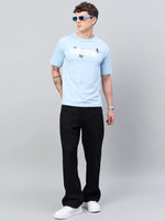 Man in 98degreenorth Men Typography Printed Round Neck Sky T-shirt, black pants, white sneakers, blue sunglasses.