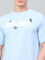 A person wears a 98degreenorth Men Typography Printed Round Neck Sky-T-shirt.