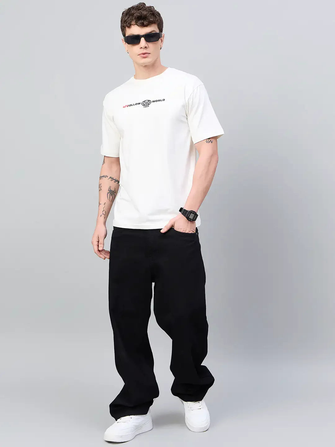Man in 98degreenorth Men Typography Printed Round Neck Offwhite T-shirt, black wide-leg pants, and white sneakers.