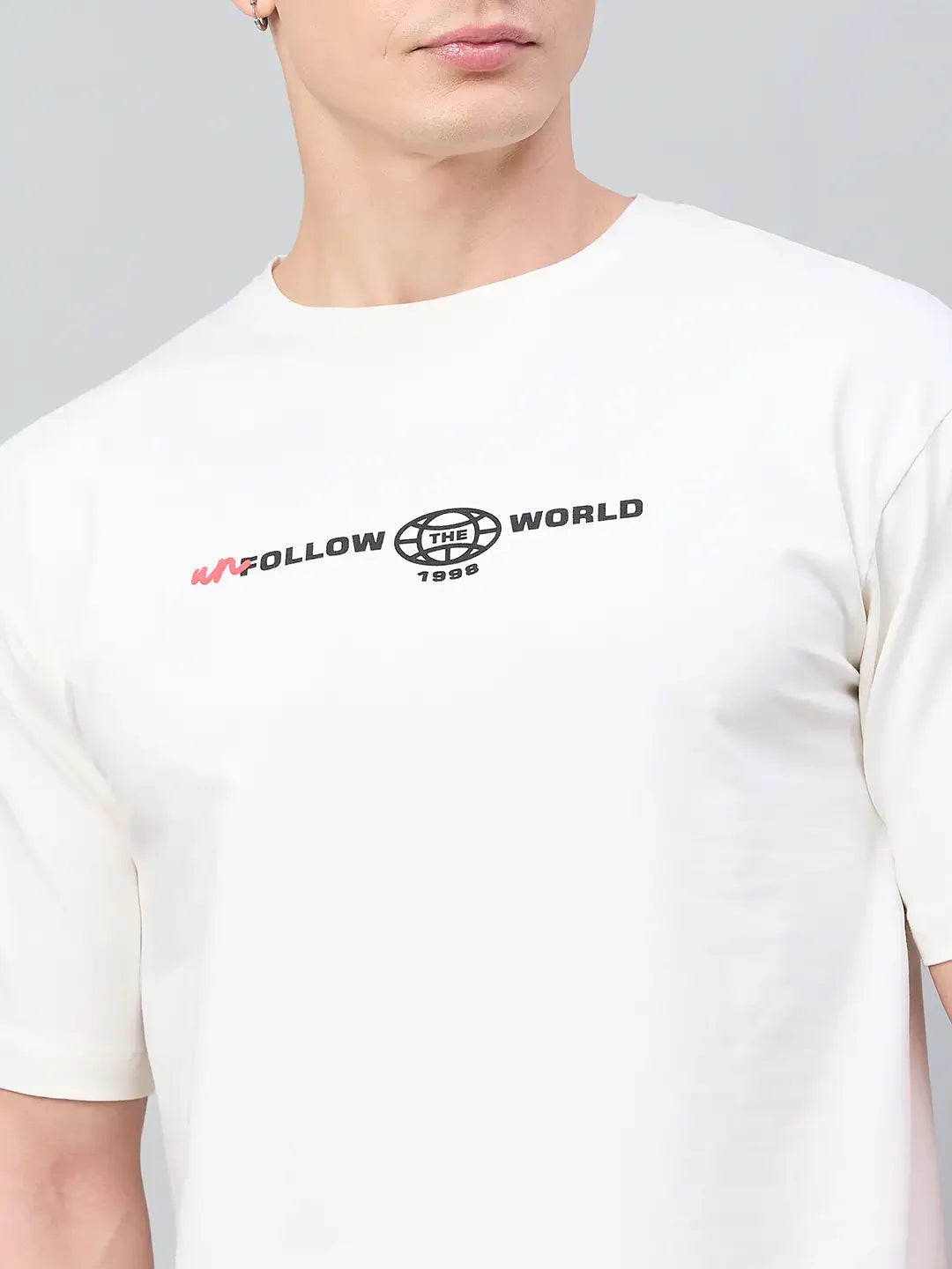 Man wears 98degreenorth Men Typography Printed Round Neck T-shirt - Offwhite with UNFOLLOW THE WORLD 1998 print.
