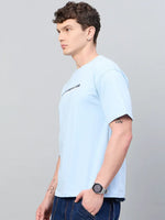 Man in 98degreenorth Men Typography Printed Sky Round Neck T-shirt and dark jeans standing sideways against gray background.