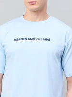 Man in a sky blue Men Typography Printed tee by 98degreenorth featuring bold HEROES AND VILLAINS text.