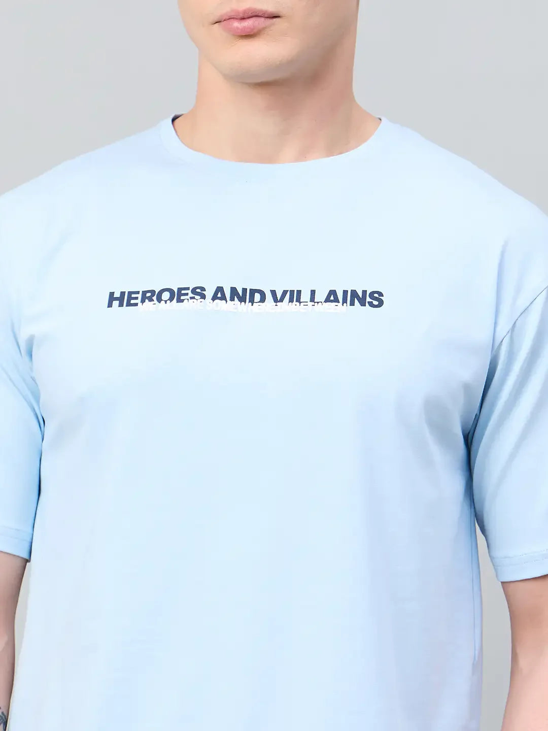 Man in a sky blue Men Typography Printed tee by 98degreenorth featuring bold HEROES AND VILLAINS text.