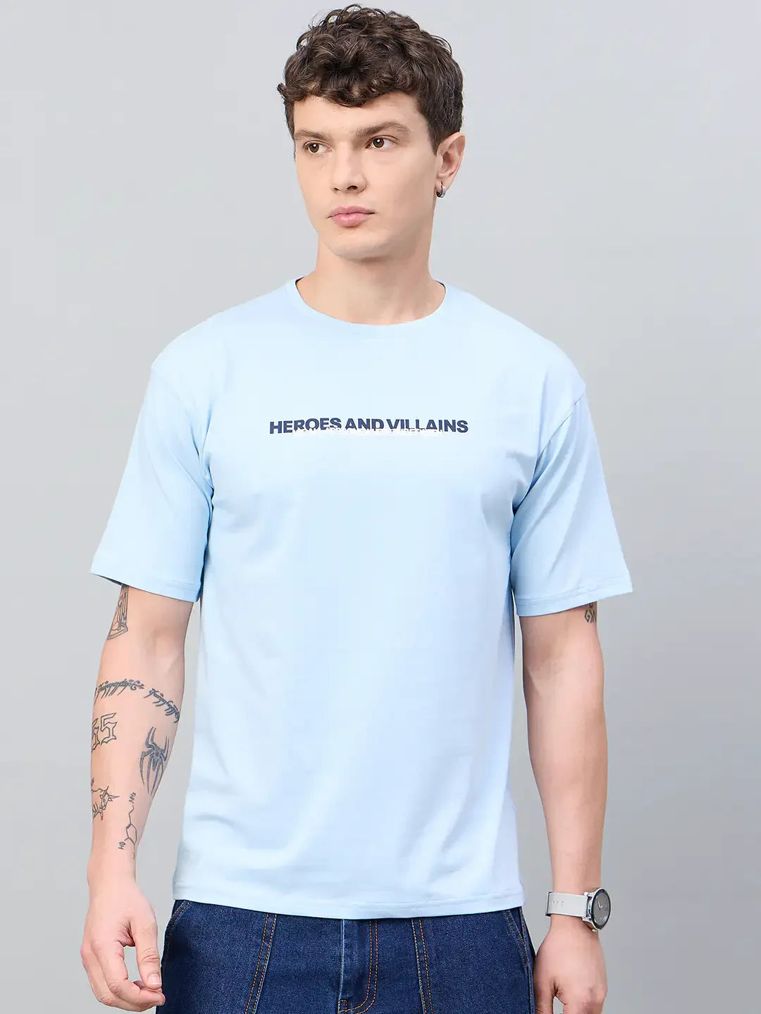 Man in a 98degreenorth Men Typography Printed Sky Round Neck T-shirt, blue jeans, and watch against a plain background.