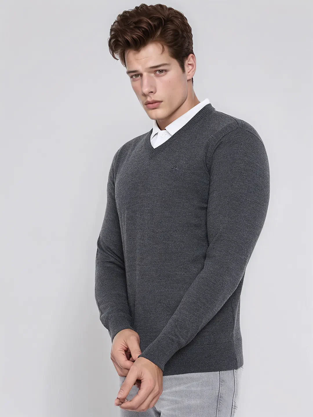 A man wears a 98degreenorth Men’s Anthra Merino Wool V-Neck Sweater, standing against a plain light background.