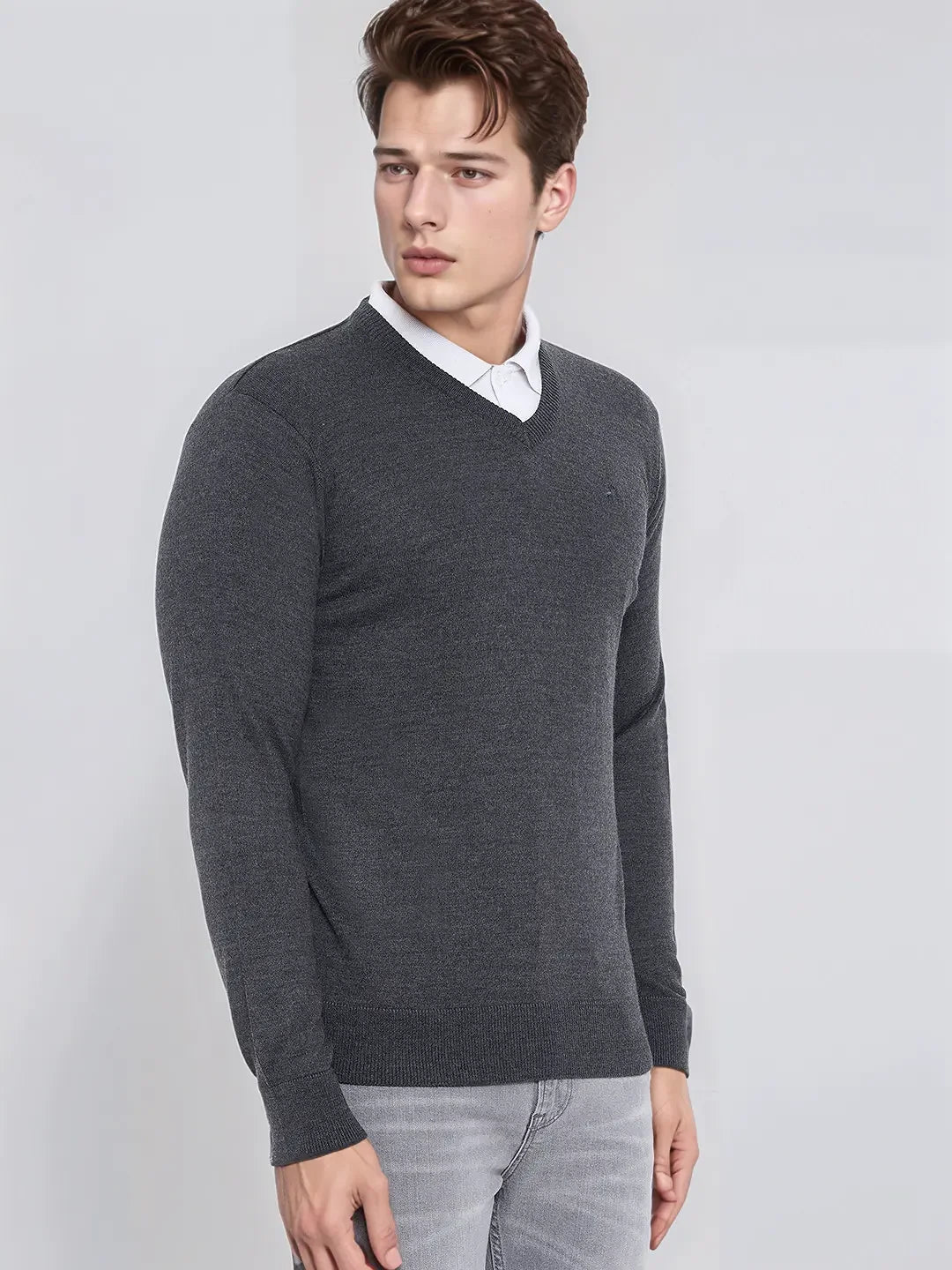 Man in 98degreenorth Men’s Anthra Merino Wool V-Neck Sweater over a white shirt and gray jeans against a plain background.