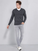 A man in glasses wears a 98degreenorth Men’s Anthra Merino Wool V-Neck Sweater with a white shirt and gray jeans indoors.