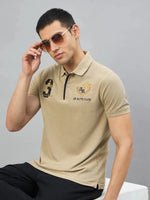 Man in 98degreenorth Men's Beige Aero Club No.3 Polo T-Shirt and sunglasses sits on a white bench against a gray background.