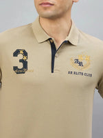 A man wears the 98degreenorth Men's Beige Aero Club No.3 Polo T-Shirt with chest embroidery.