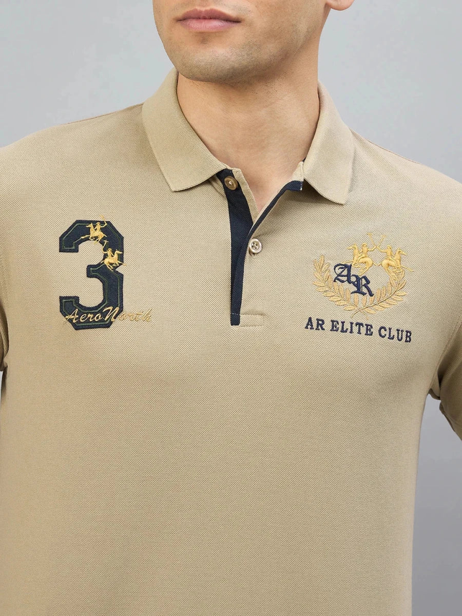 A man wears the 98degreenorth Men's Beige Aero Club No.3 Polo T-Shirt with chest embroidery.