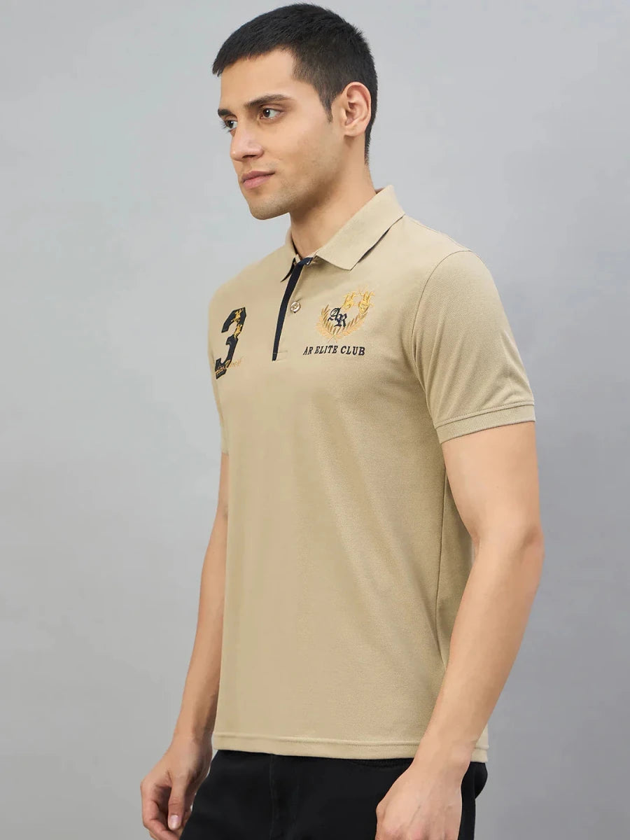Man wearing a Men's Beige Aero Club No.3 Polo T-Shirt by 98degreenorth, standing against a plain gray background.