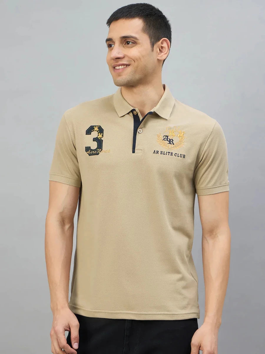 Man in 98degreenorth Men's Beige Aero Club No.3 Polo T-Shirt, smiling against a plain gray background.