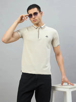 Man in 98degreenorth Men's Beige Polo T-Shirt — Handmade Series with contrast tipping poses by a white stool.