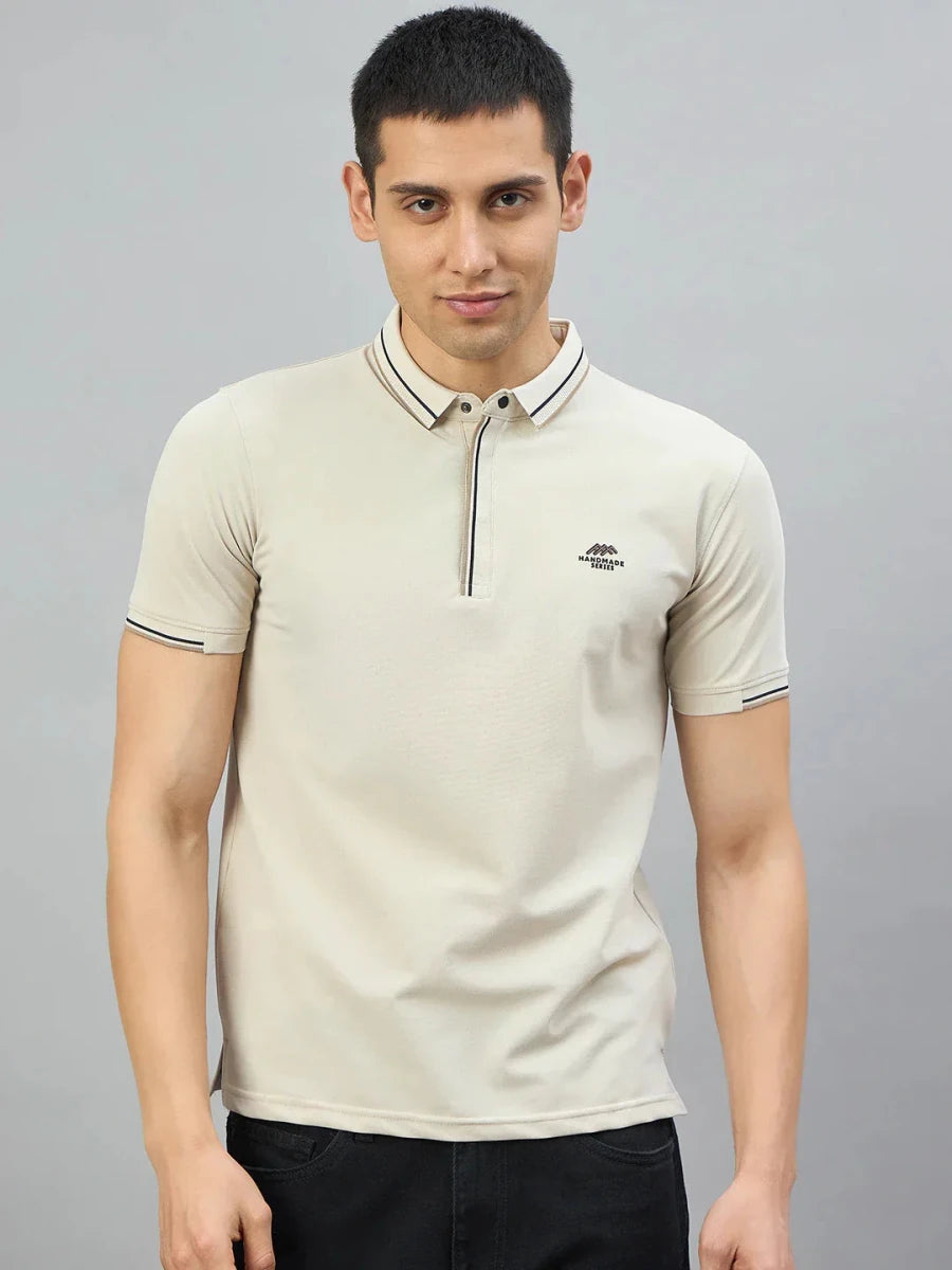 Man in 98degreenorth Men's Beige Polo T-Shirt—Handmade Series, contrast tipping, on a plain gray background.