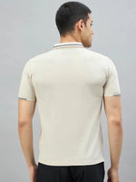 Man with short dark hair wears 98degreenorth Men's Beige Polo T-Shirt—Handmade Series, facing away against plain background.