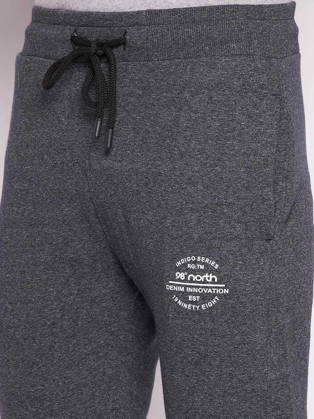 Close-up of 98degreenorth Men’s Black Jaspe Fleece Trackpants with drawstring waist and white text near left pocket.