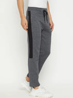 A person wears 98degreenorth Men’s Black Jaspe Fleece Trackpants with side panel and white sneakers, against a plain background.