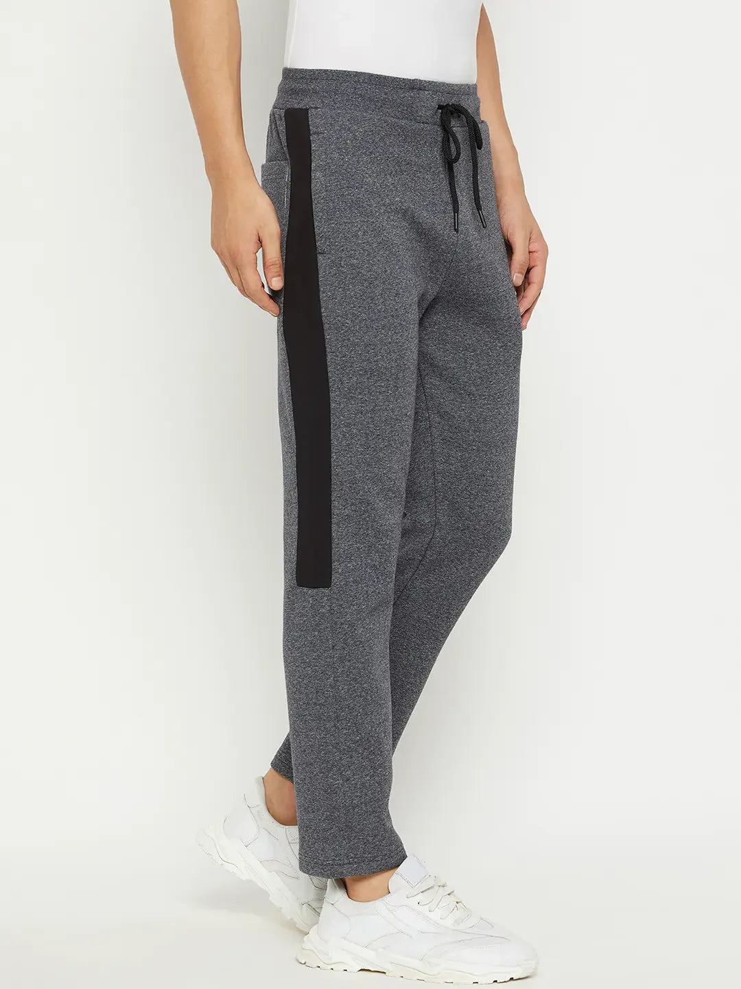 A person wears 98degreenorth Men’s Black Jaspe Fleece Trackpants with side panel and white sneakers, against a plain background.