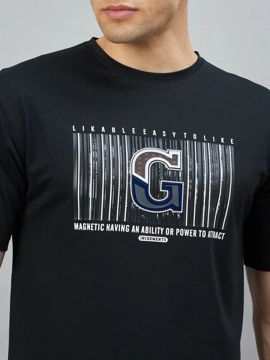 A man wears the 98degreenorth Men’s Black Magnetic Graphic T-Shirt—Cotton Lycra, featuring bold streetwear style.