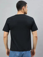 A man wears the 98degreenorth Men's Black Magnetic Graphic T-Shirt, standing with his back to the camera.